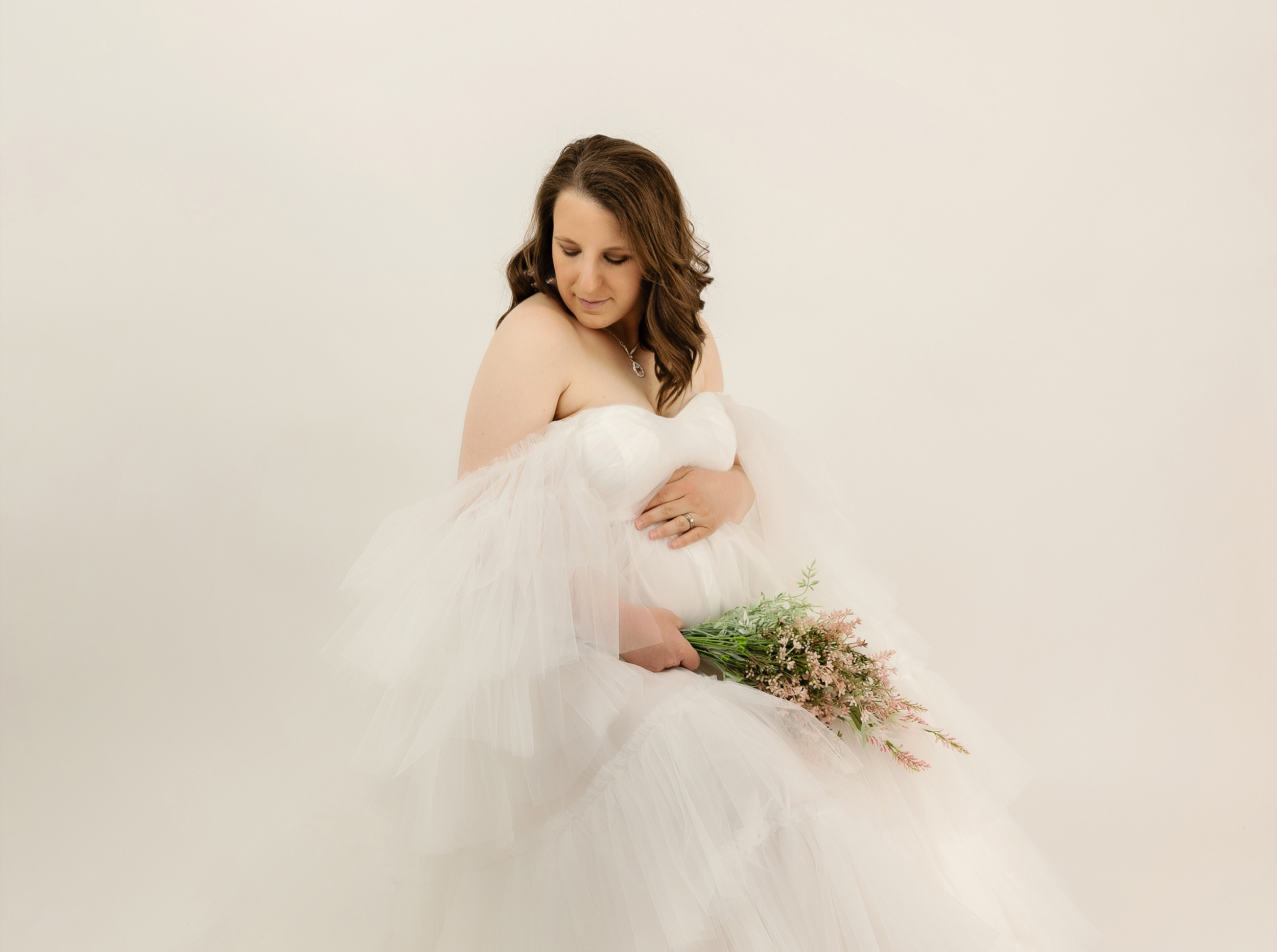 Maternity photo of a woman in a white dress in an Erie, Pa photography studio