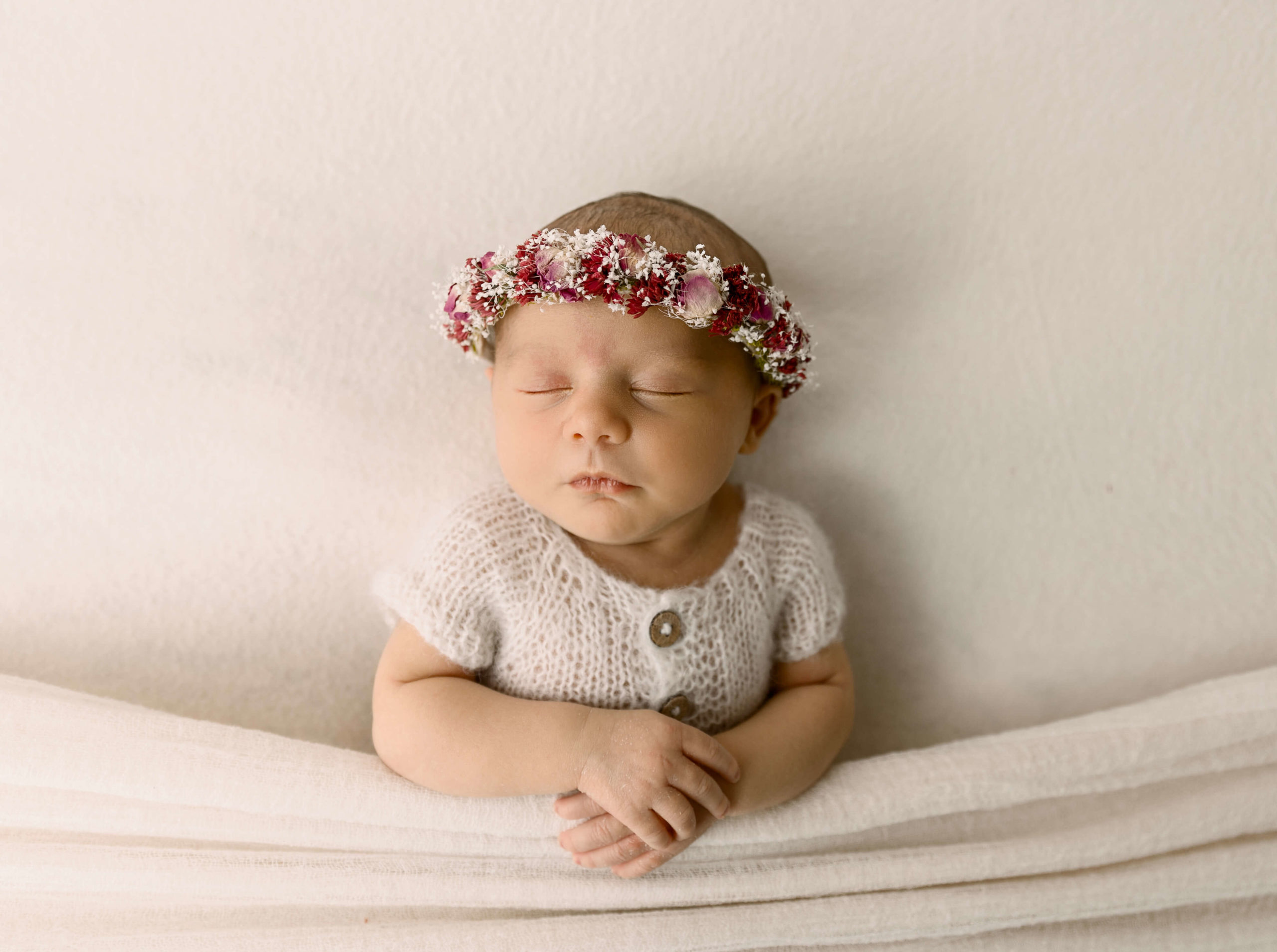 Newborn photo of a baby girl wearing a beautiful flower headband.