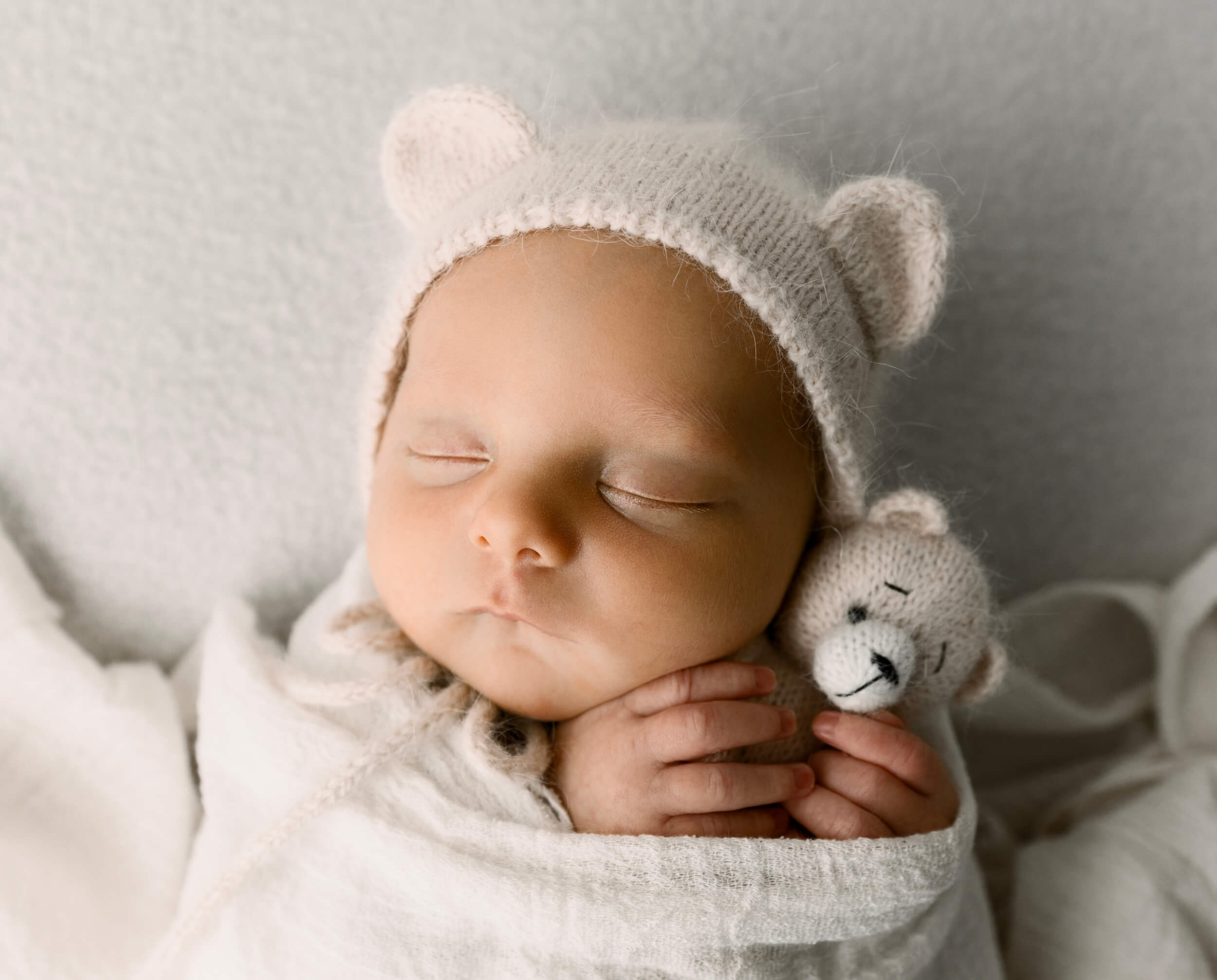Baby boy holding a teddy bear with teddy bear bonnet