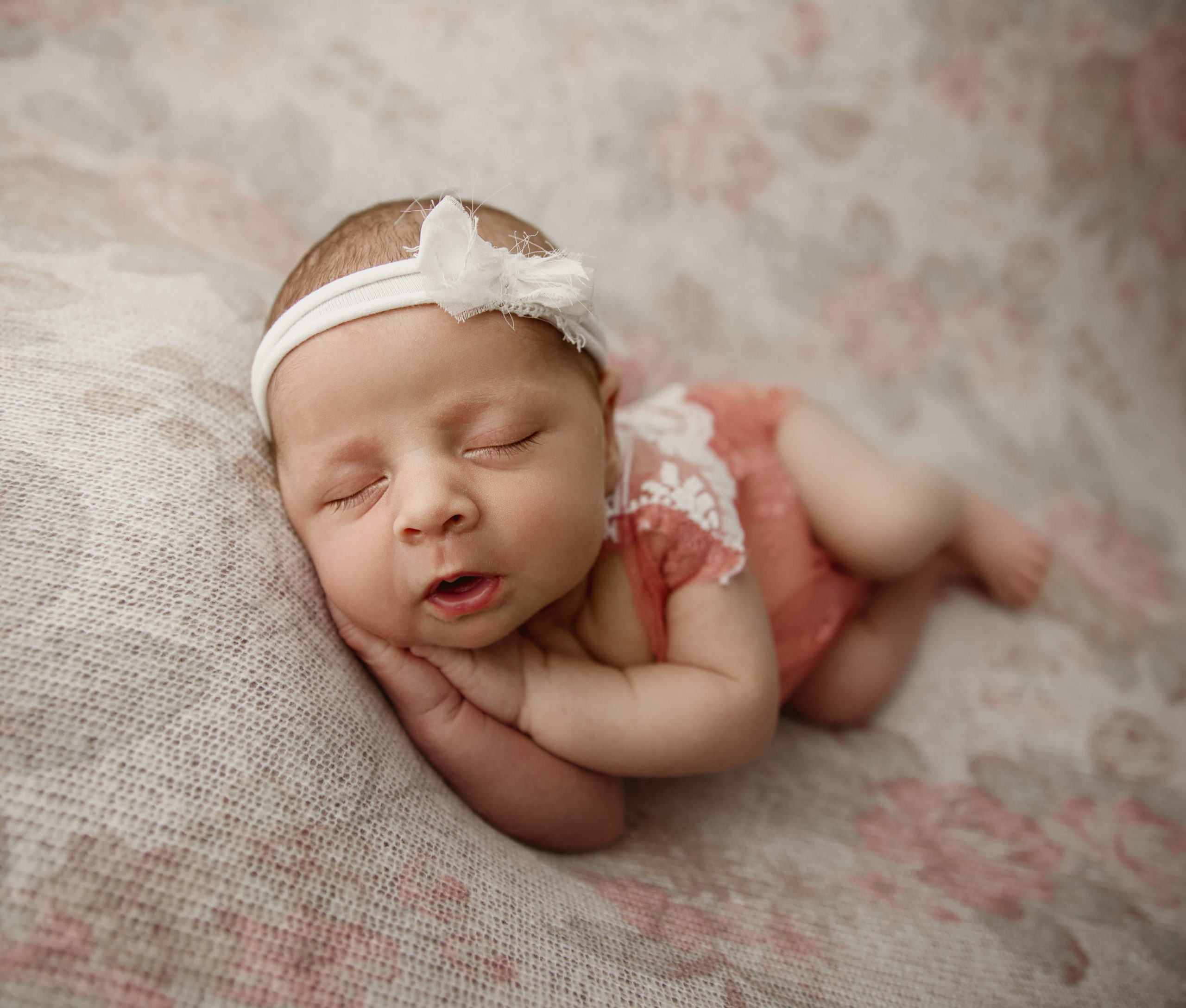 Photo of a newborn baby girl in a pink romper