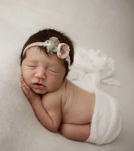 Newborn baby girl with a pretty headband in bum up pose
