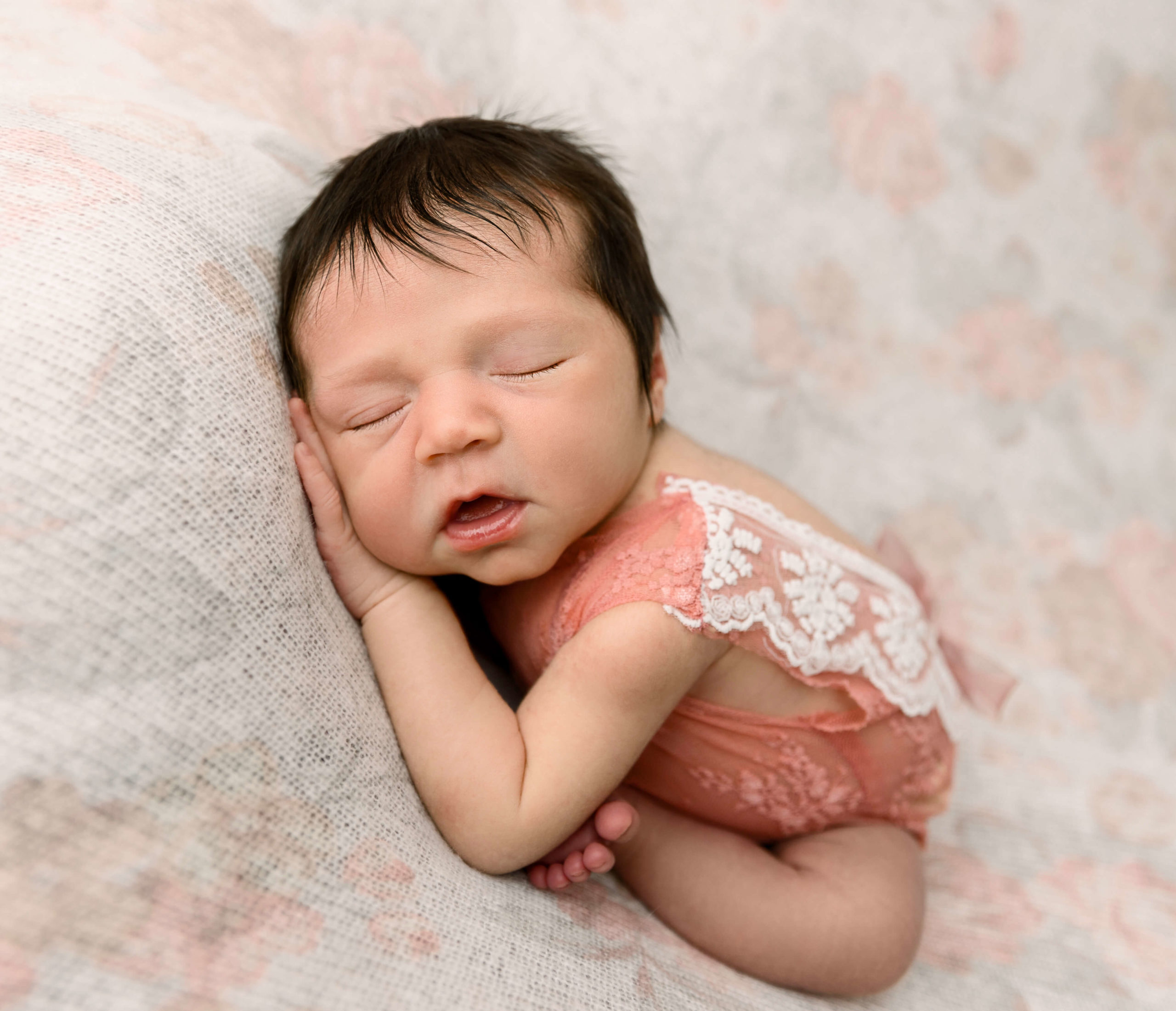 Newborn portrait of a baby girl sleeping on a flower backdrop