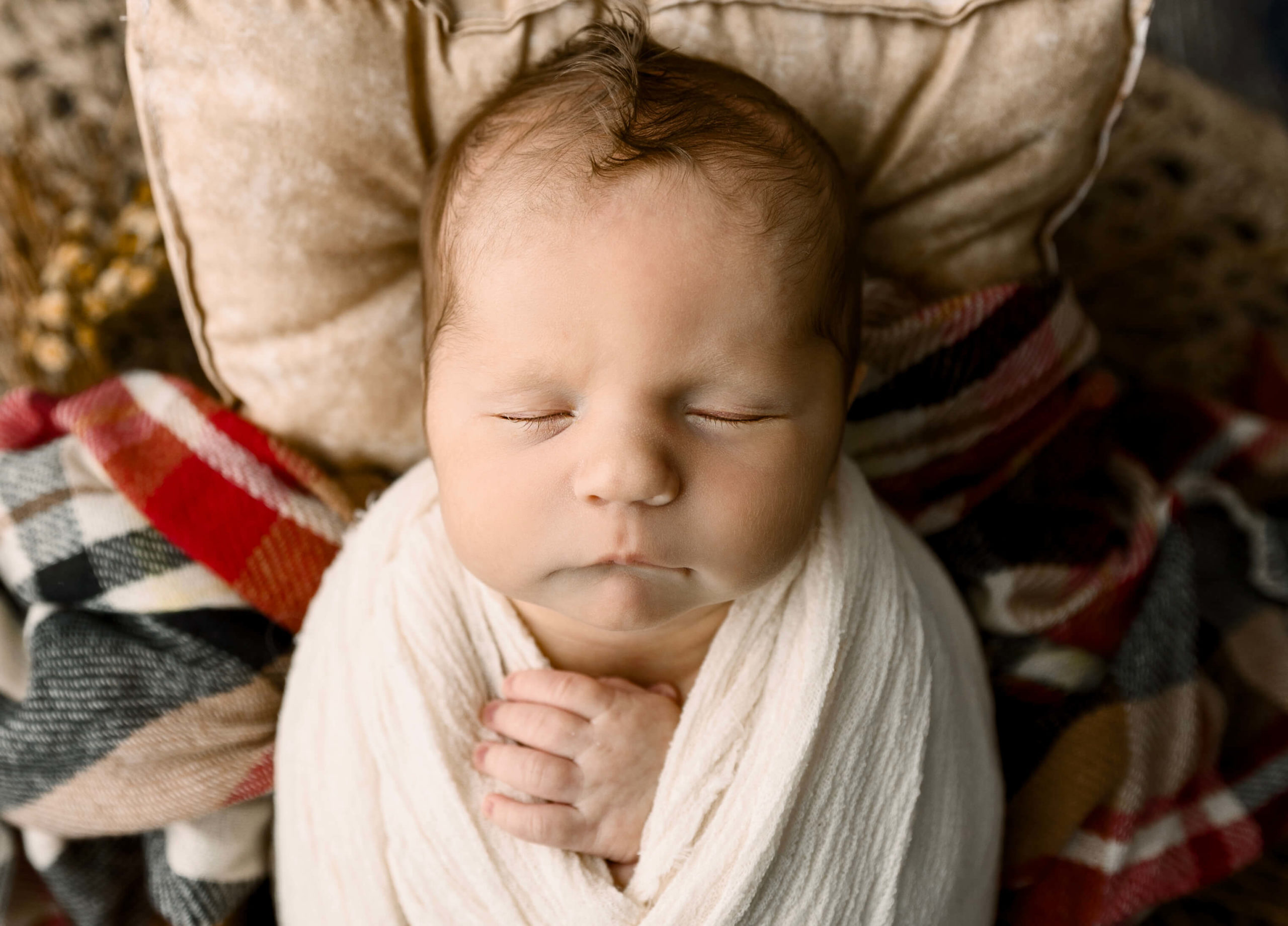 Newborn baby boy laying on a plaid blanket