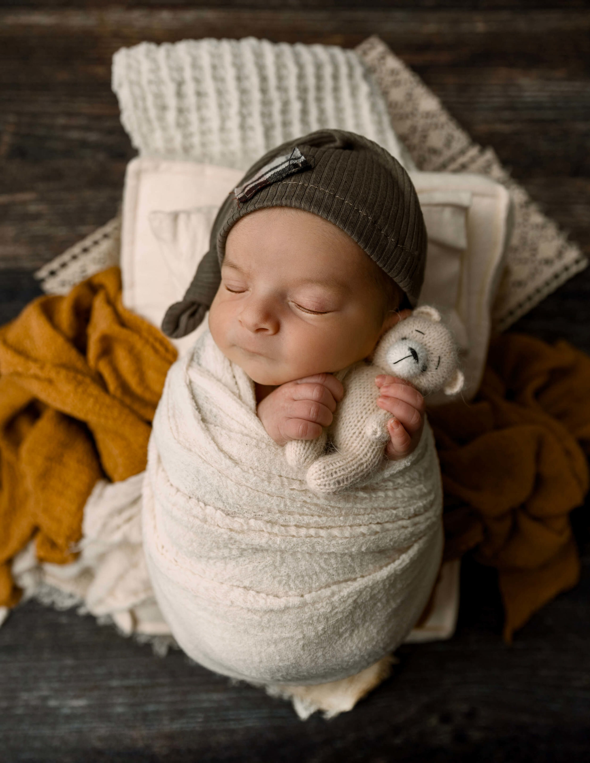Baby boy with a sleepy cap holding a teddy bear