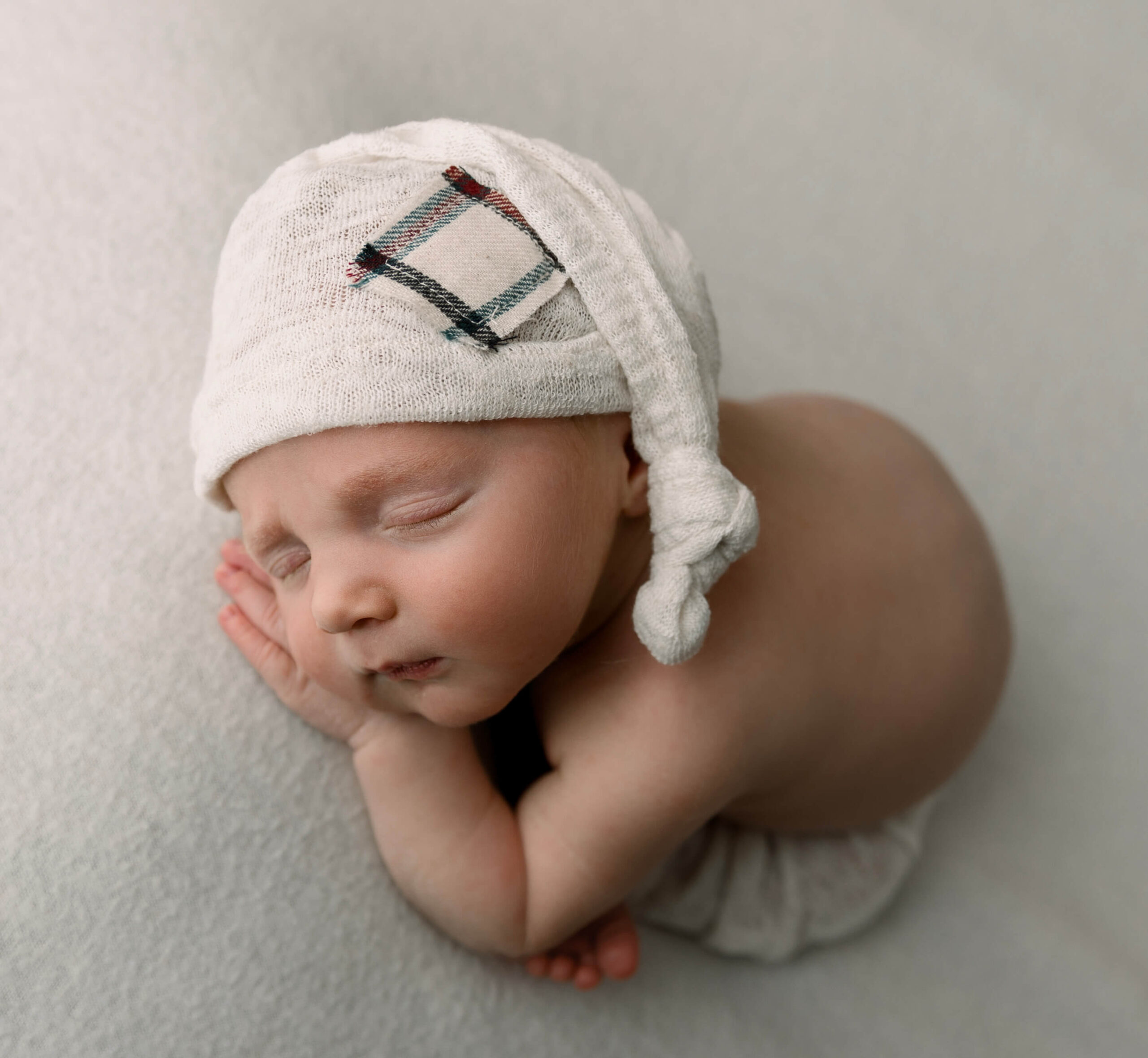 Photo of a new ewborn baby boy with a sleepy cap taken in an Erie Pa photography studio