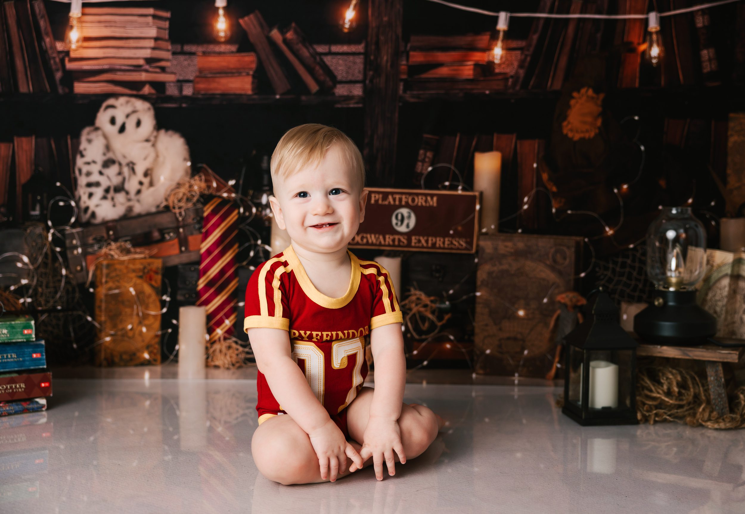 A happy toddler boy in a Gryffindor jersey sits in a Harry Potter Themed studio before visiting an indoor playground erie pa