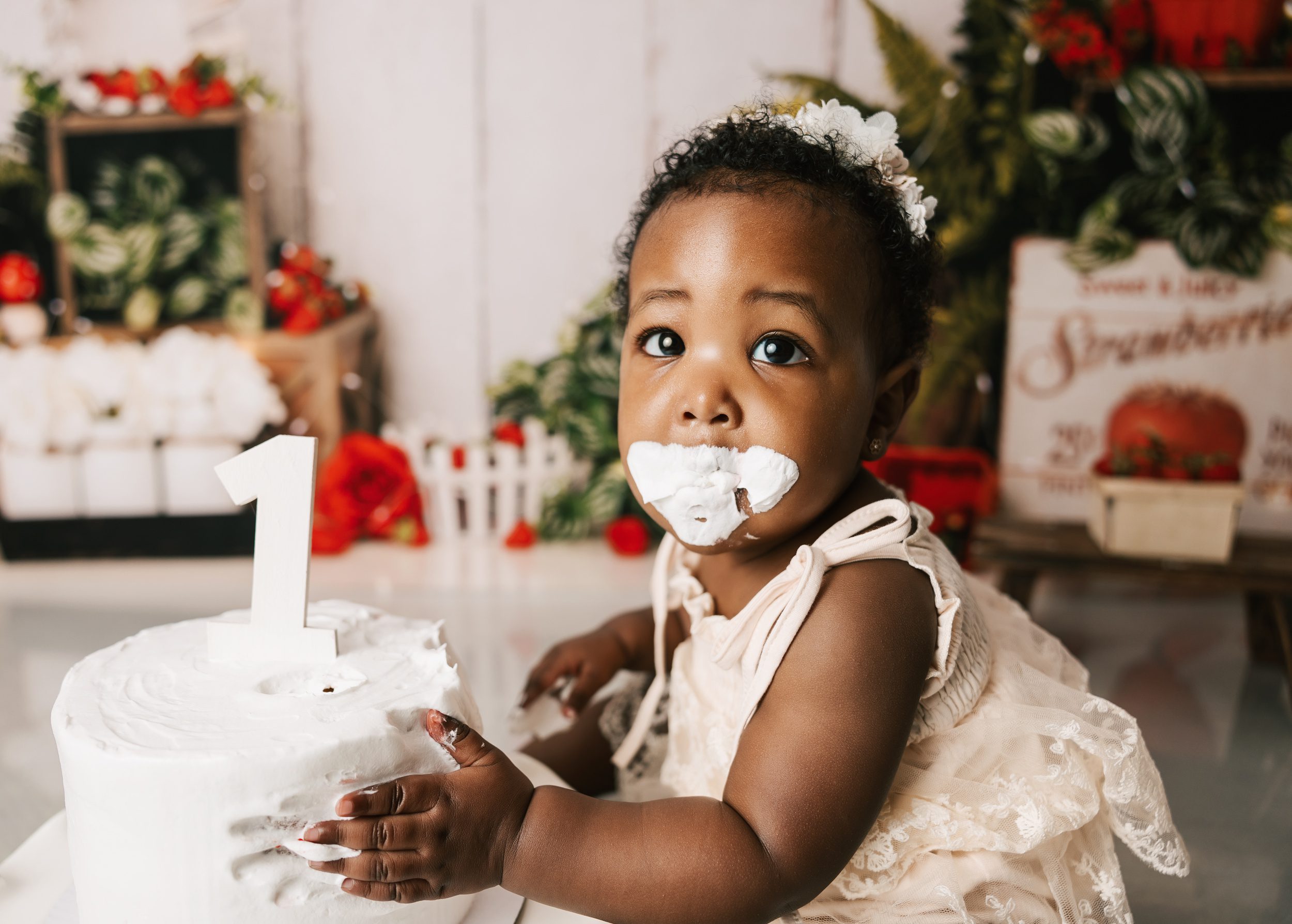 A toddler girl with her face covered in icing plays with her birthday cake before visiting kid friendly restaurants erie pa