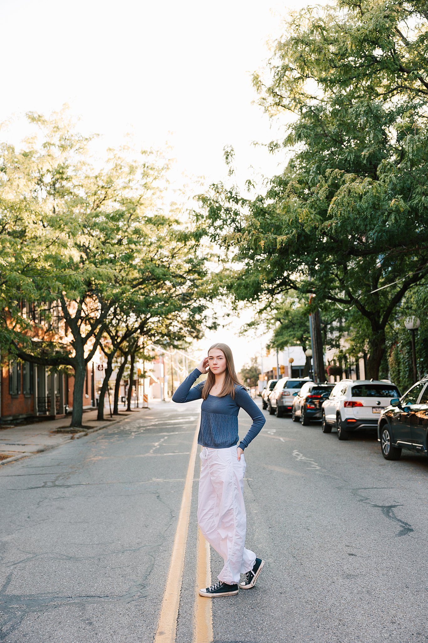 A high school senior with long brown hair stands in a downtown street in white pants after finding tutoring erie pa